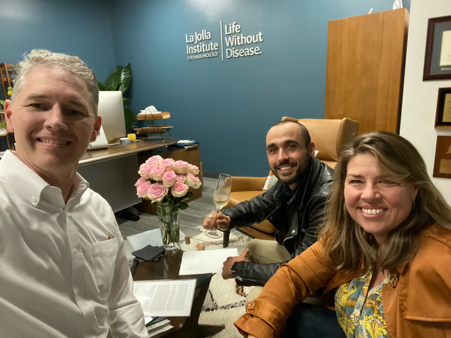 Reina (center) signs his agreement to join the LJI faculty with LJI Professor and Chief Scientific Officer Shane Crotty, Ph.D. (left) and LJI Professor, President, and CEO Erica Ollmann Saphire, Ph.D., MBA (left).