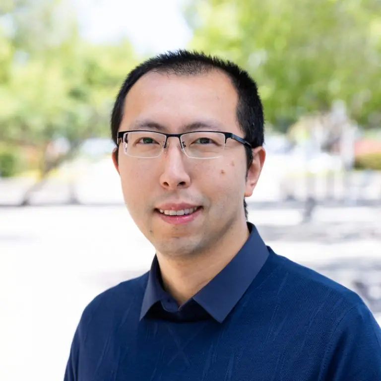 Portrait photo of Haoyang Li. He is standing outside and smiling at the camera