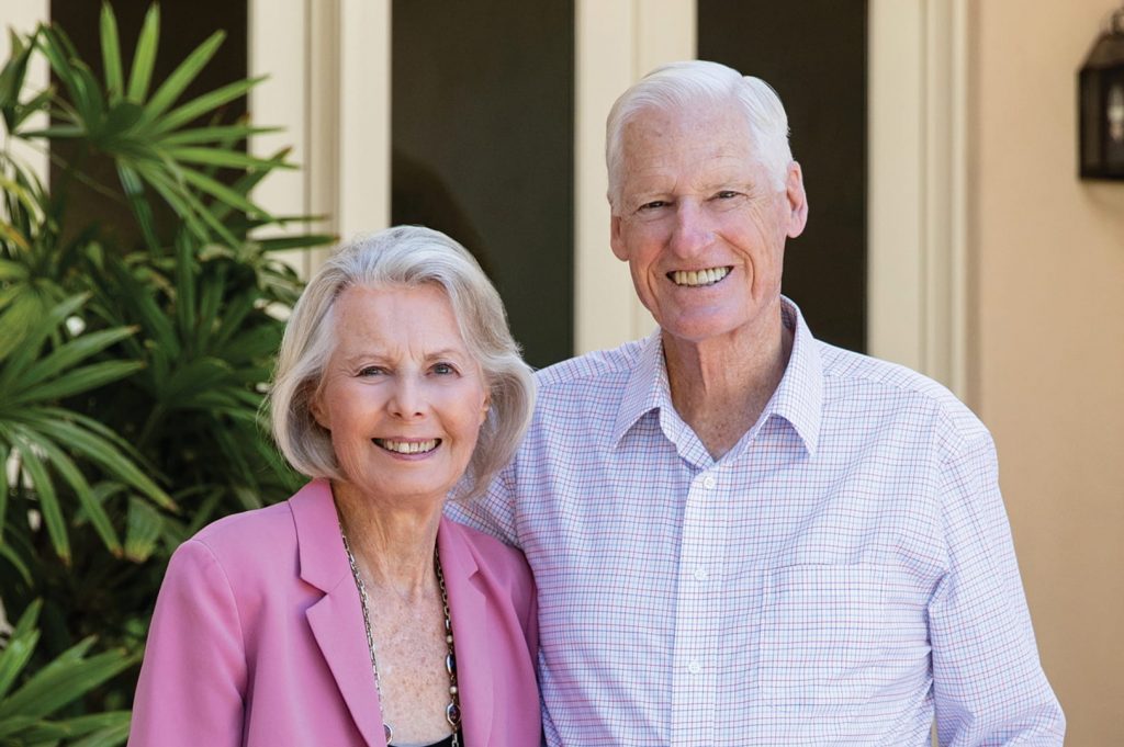 Photo portrait of Dick and Karna Bodman. They are standing outside and smiling at the camera