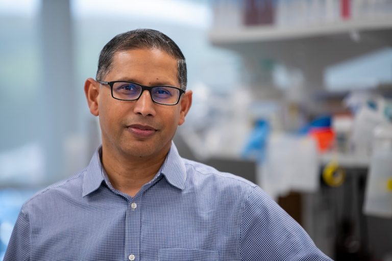 Portrait photo of Dr. Vijayanand. He is standing in a laboratory and looking at the camera