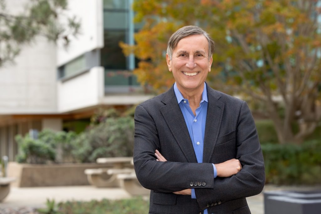 Portrait photo of Dr. Sette. He is wearing a suit and standing outside. He is crossing his arms and smiling at the camera.